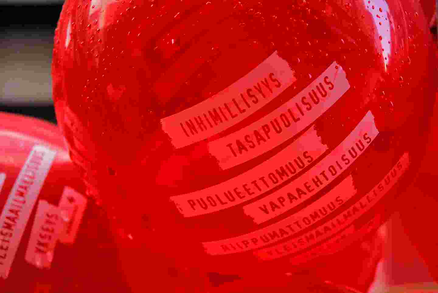 Kaksi punaista ilmapalloa, joissa lukee sanoja, kuten inhmillisyys ja vapaaehtoisuus. 