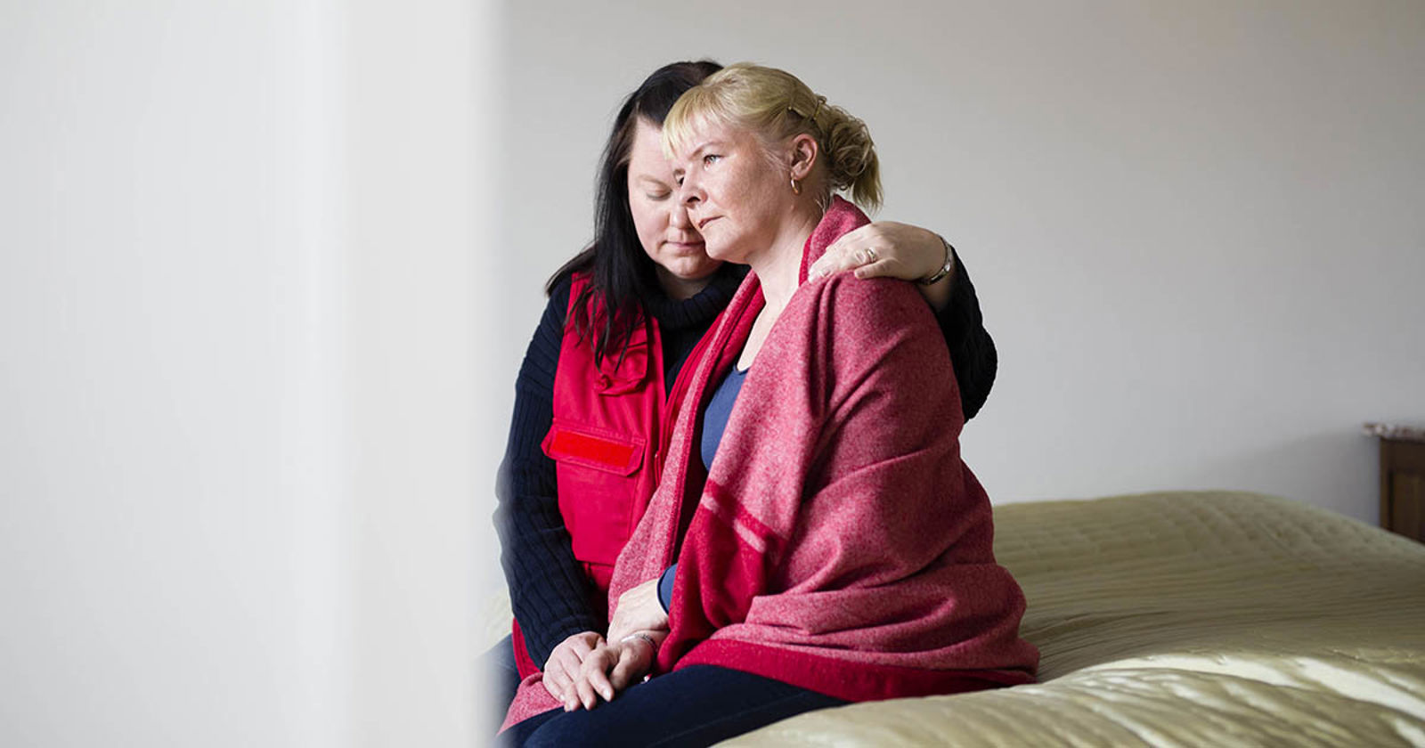 Henkilö Puniasen Ristin liiveissä pitää kättään toisen ihmisen harteilla.