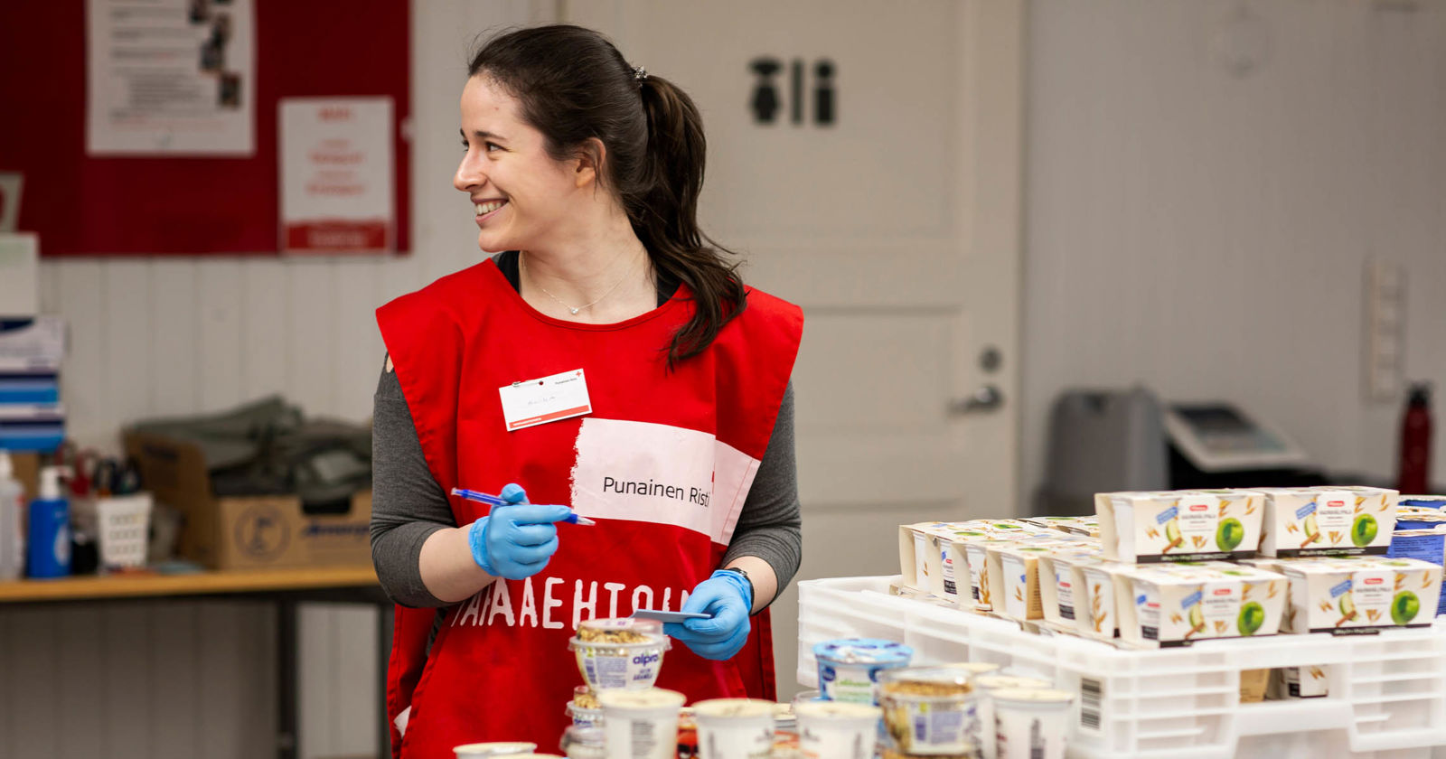 Ihminen Punaisen Ristin liivissä jakamassa ruokaa.