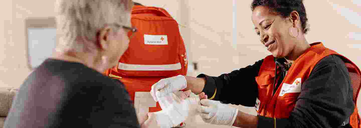 Röda Korsets frivillig bandagerar en persons sår.