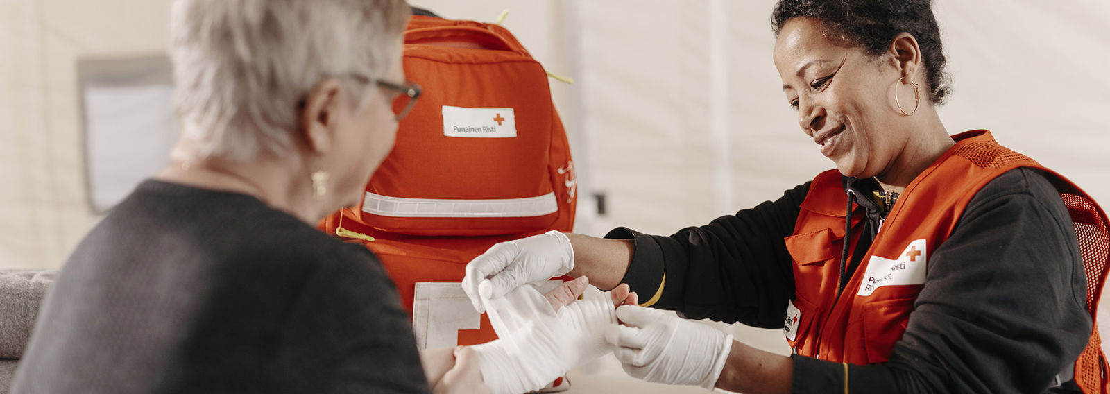 Röda Korsets frivillig bandagerar en persons sår.