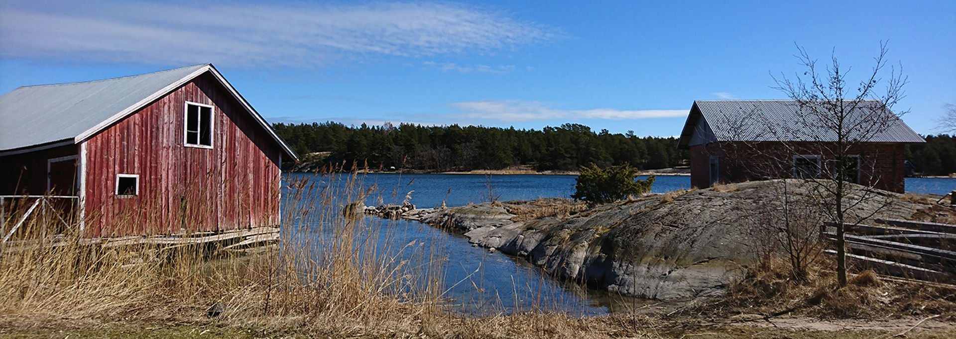 Strand på Houtskär med en röd båthus och havet på våren