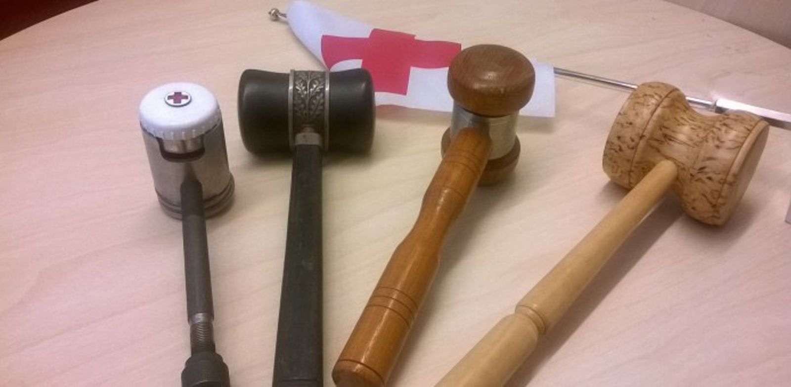 Pöydällä on neljä nuijaa ja Punaisen Ristin pieni lippu.