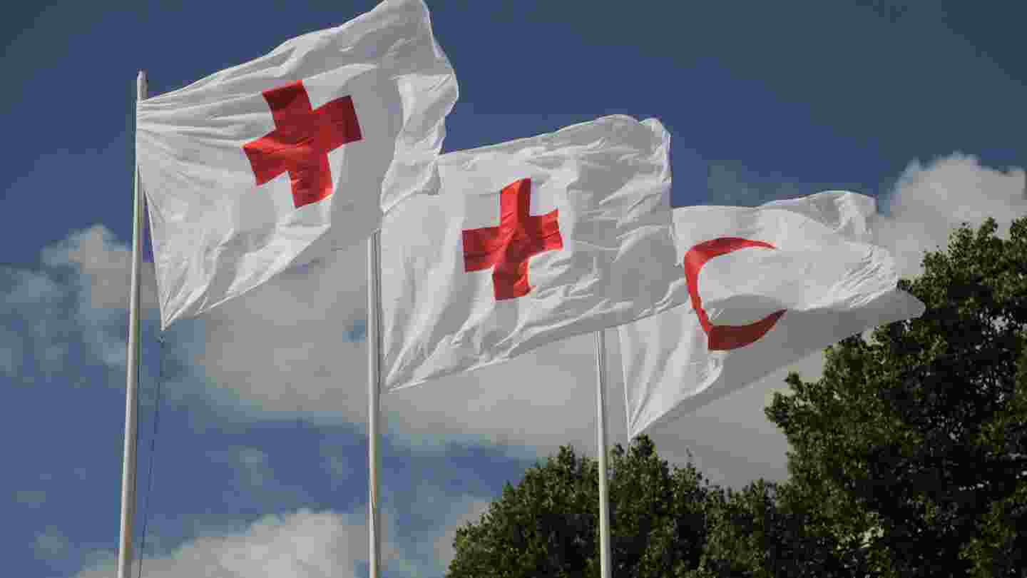 Punaisen Ristin lippuja liehumassa mastossa.