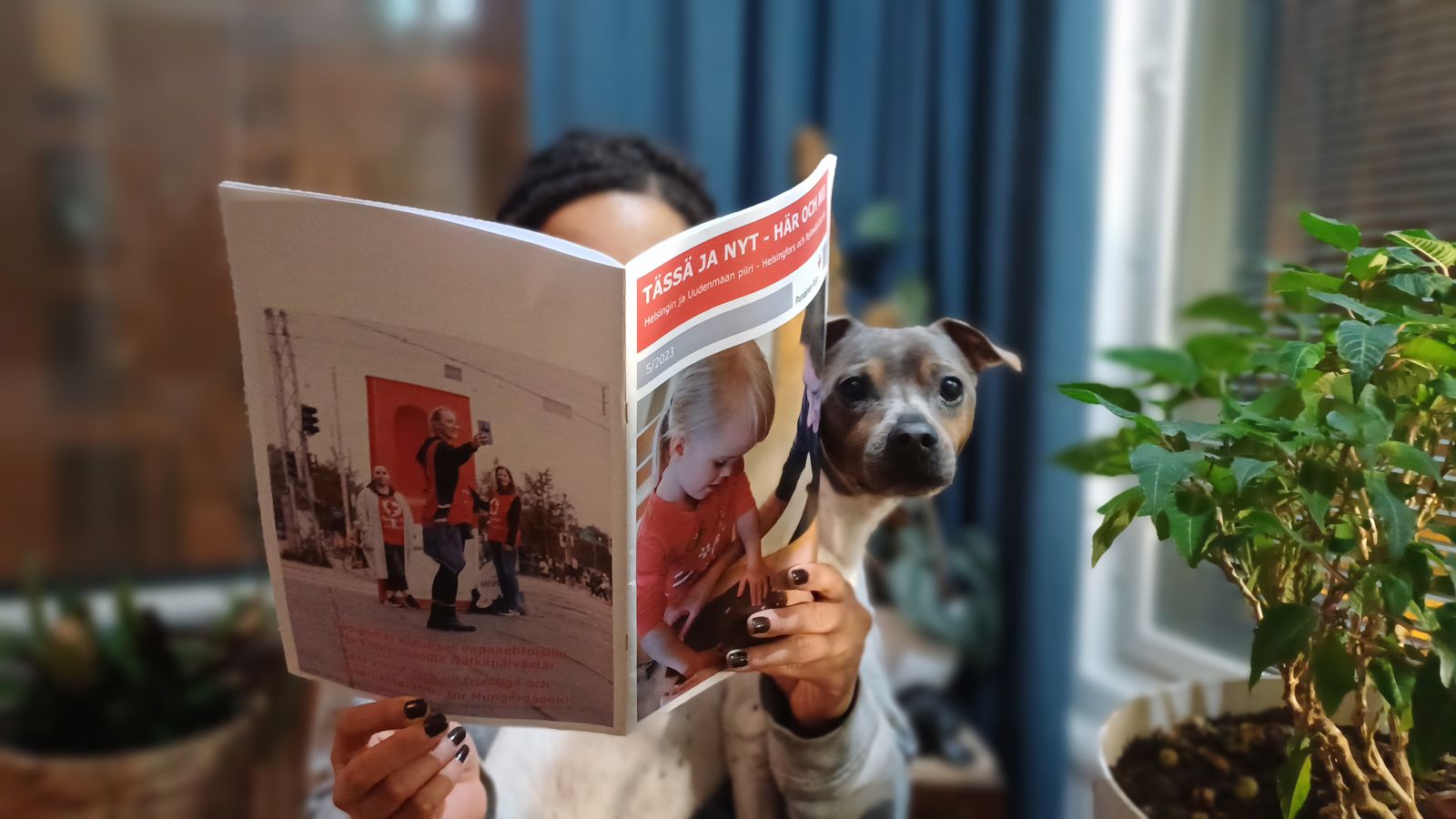 Helsingin ja Uudenmaan piirin uutiset jaetaan sähköisillä uutiskirjeillä. Kuvassa nuori henkilö lukee vanhaa lehteämme koira sylissään.