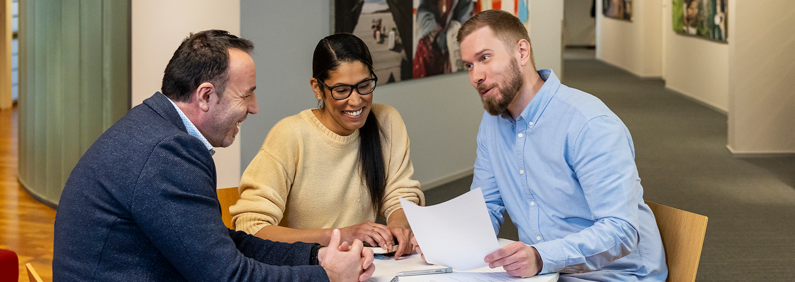 Kolme henkilöä istuu pöydän ääressä.