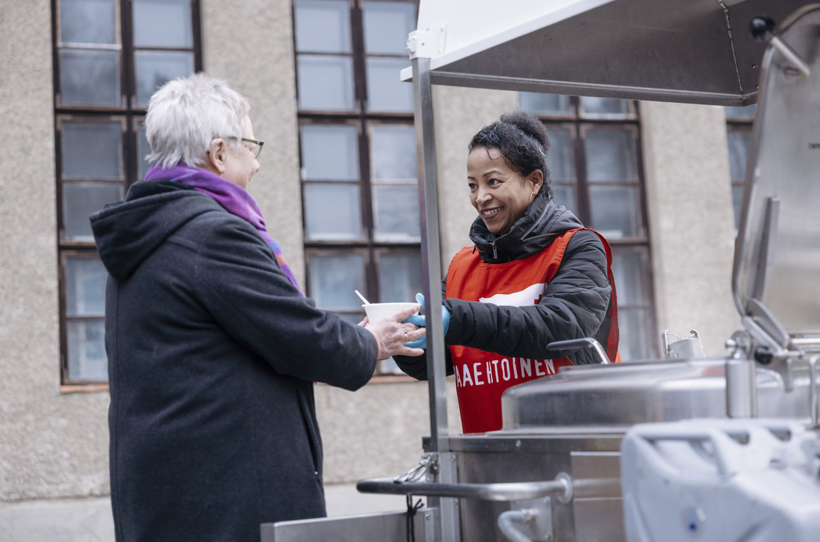 Ihminen Punaisen Ristin liiveissä jakaa ruokaa muille ihmisille