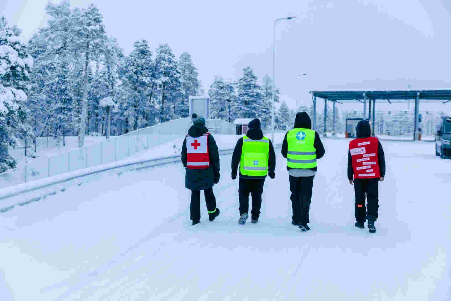 Kaksi ihmistä kypärissä ja Punaisen Ristin liiveissä pitelee putkea