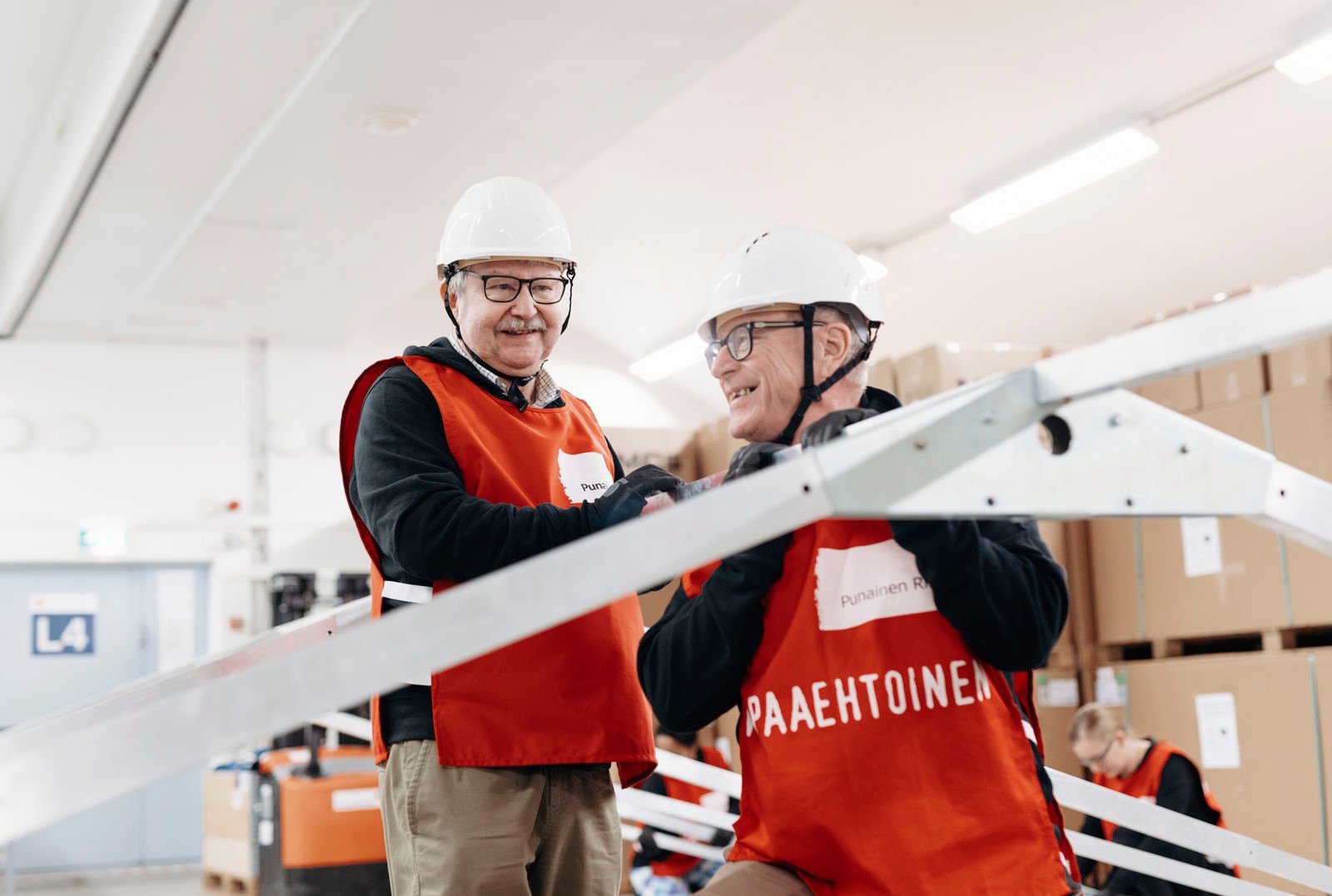 Kaksi ihmistä nostamassa yhdessä putkea