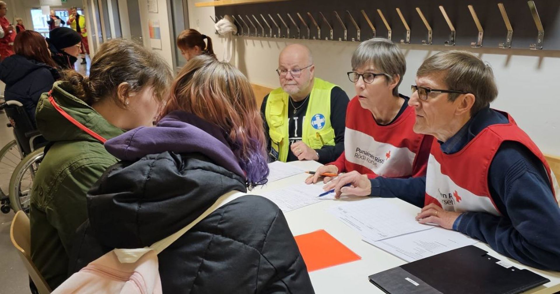 Vapaaehtoisia Punaisen Ristin liiveissä valmiusharjoituksessa pöydän ääressä. 