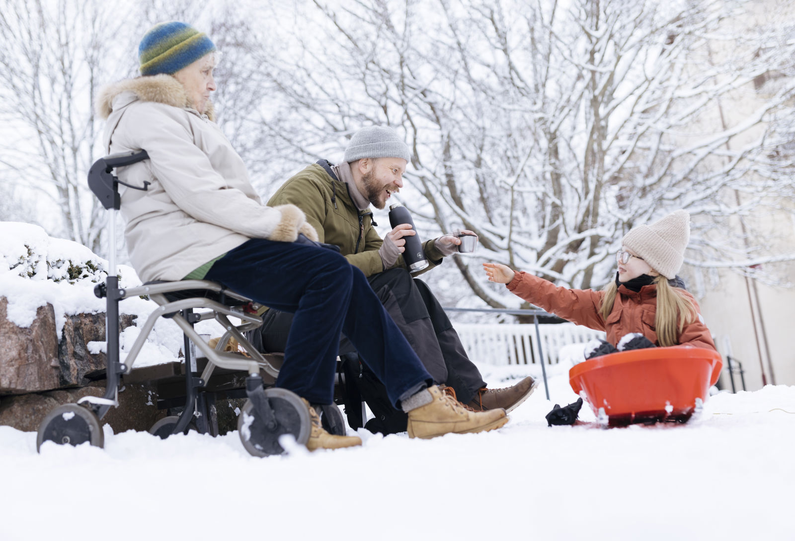 Kaksi aikuista ja lapsi viettävät talvista päivää ulkona. 