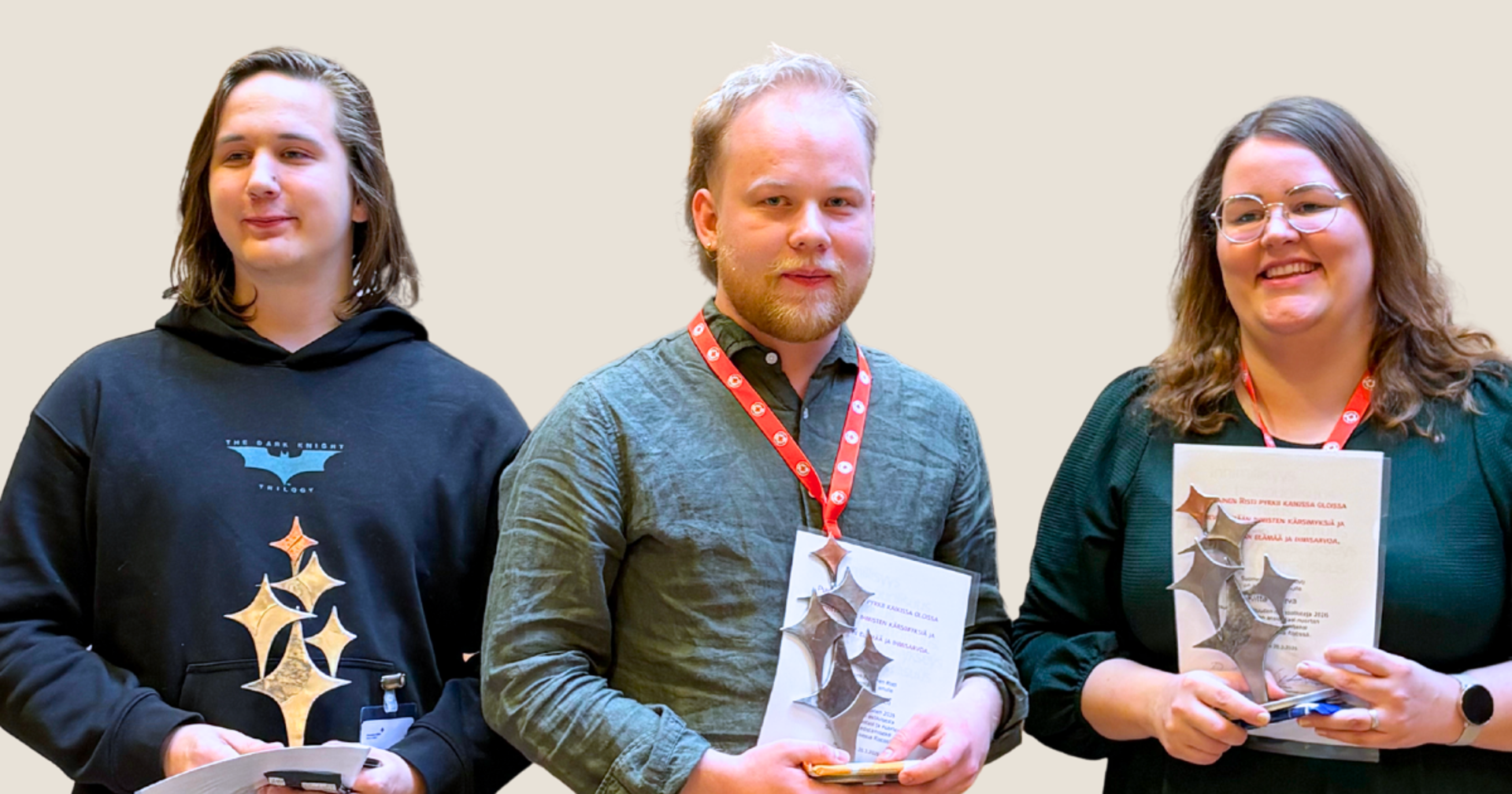 Valokuvassa kolme henkilöä kuvattuna vierekkäin vyötäröstä ylöspäin. Kaikilla on sylissään palkintopokaali (hopeisen värisiä tähtikuvioita kohoaa puisesta jalustasta).)