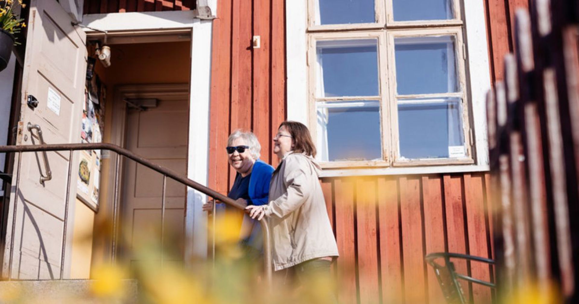 Kaksi henkilöä kävelee yhdessä kohti kohtaamispaikan avointa ovea.
