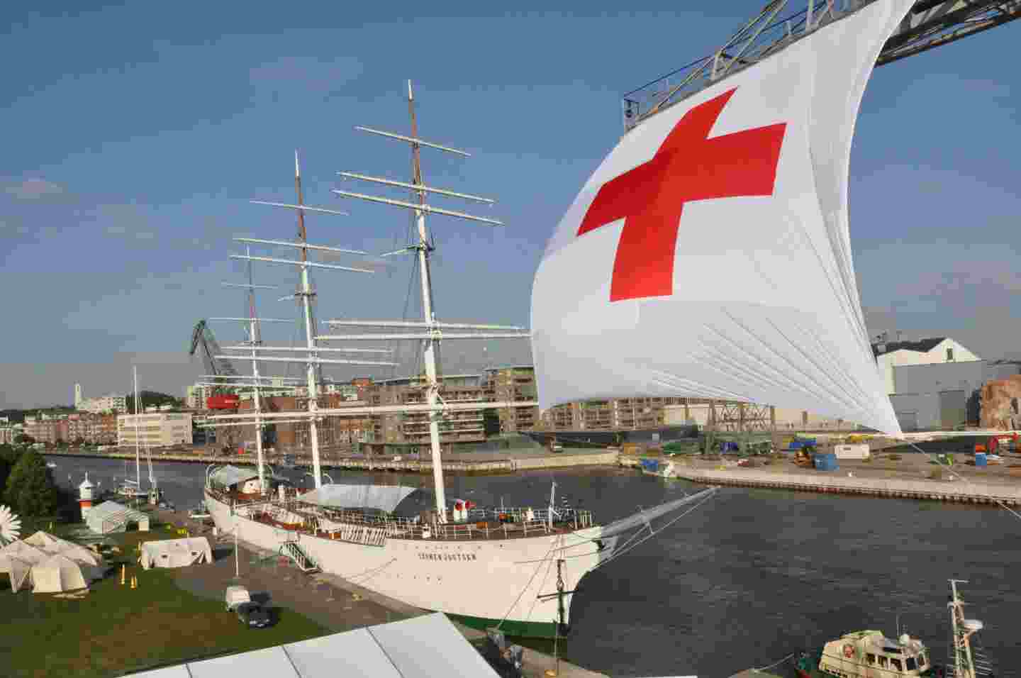 Suomen Joutsen laiva Aurajoessa, jonka edessä jättimäinen lippu, jossa punainen risti.