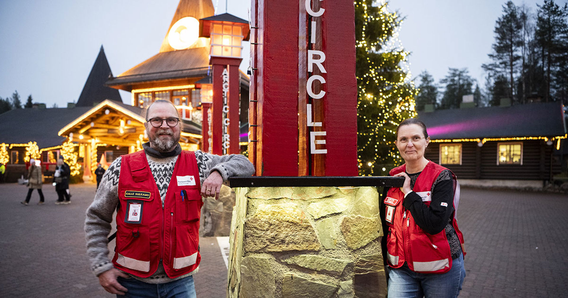 Kaksi hymyilevää henkilöä ulkona.