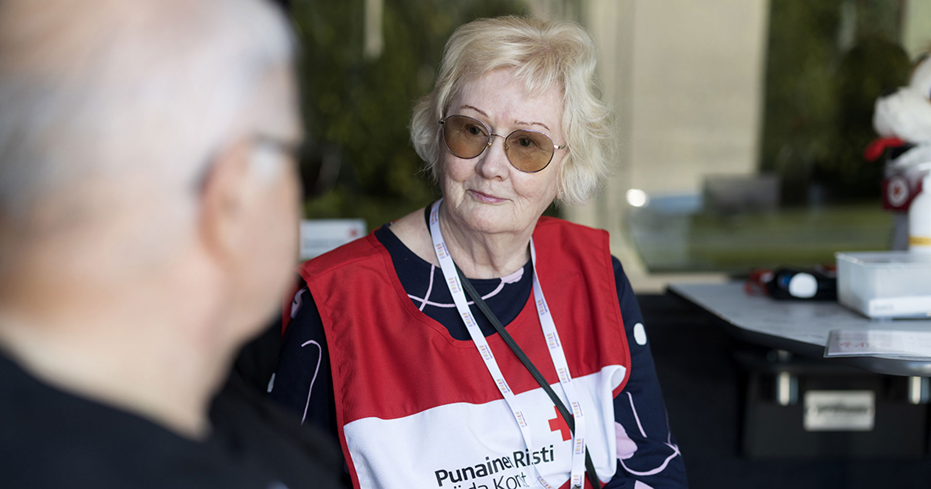 Punaisen Ristin vapaaehtoinen istumassa kasvot kohti toista henkilöä.