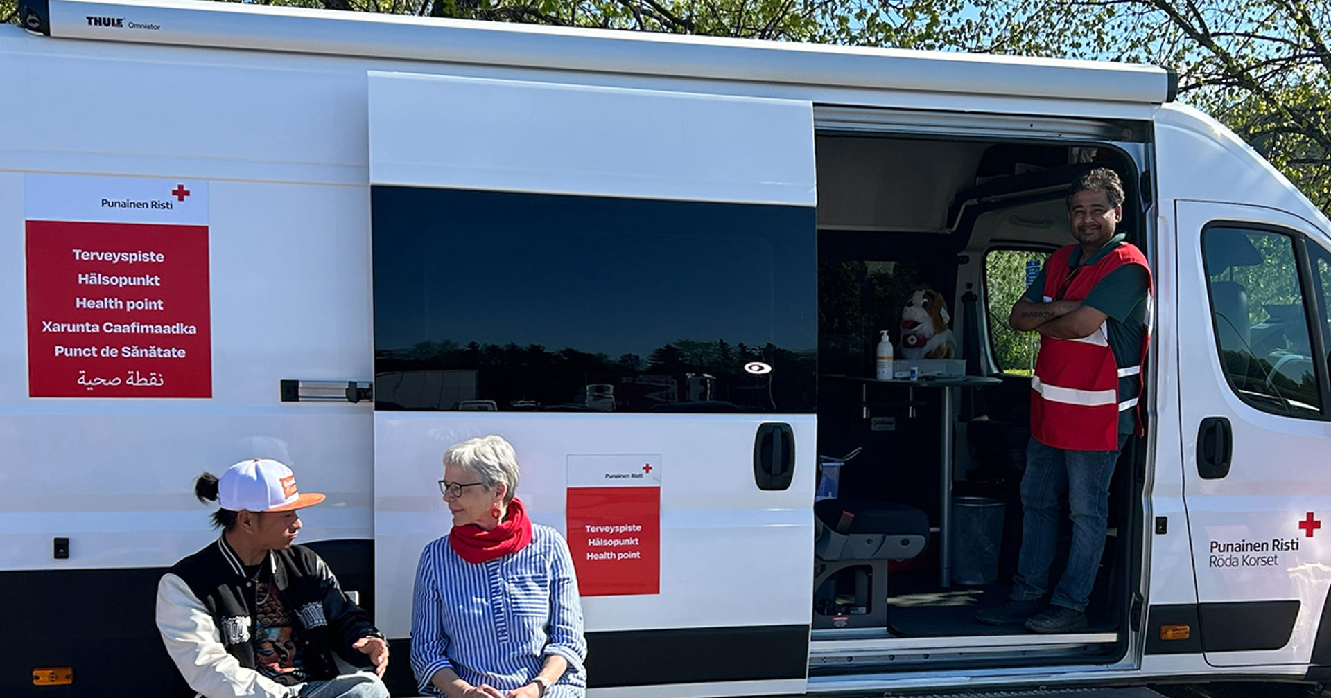 Punaisen Ristin Liikkuva Terveyspiste, jonka edustalla ihmisiä. 