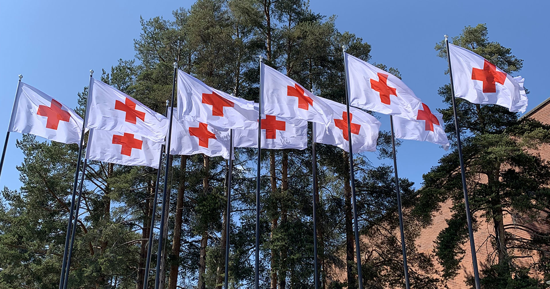 Punaisen Ristin lippuja liehumassa lipputangossa.