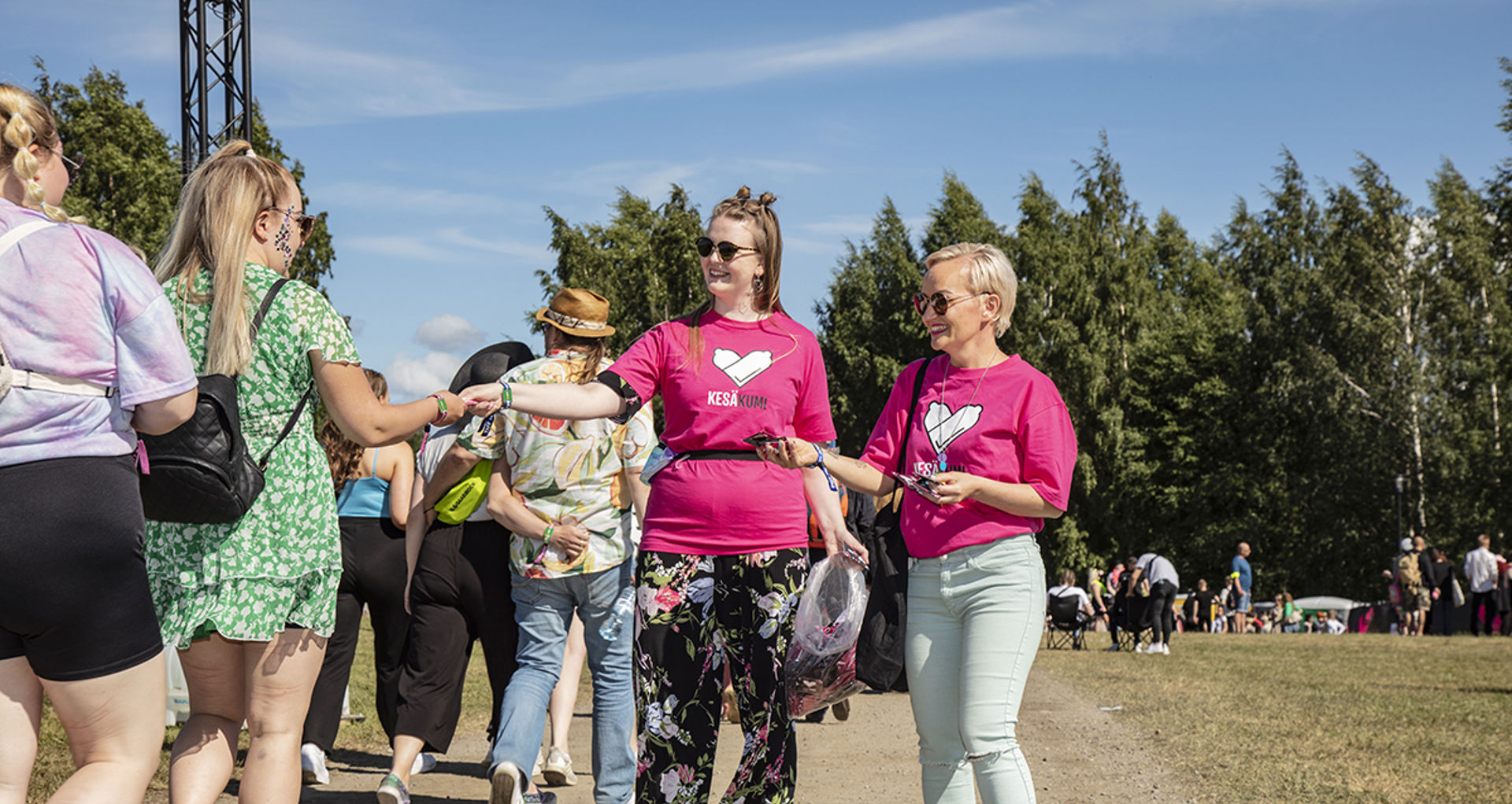 Kaksi henkilöä jakaa kesäkumeja festareilla. 